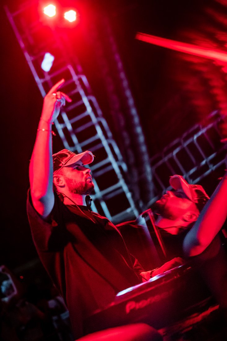 Un DJ levanta el brazo bajo la luz roja, capturado con efecto de movimiento.